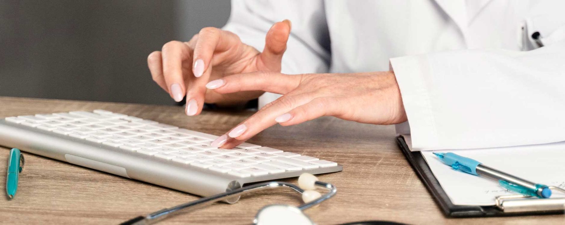 Healthcare professional typing on keyboard with stethoscope and clipboard nearby, representing medical billing companies in Pittsburgh, PA.
